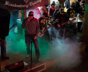 Fotos der Schweizer Band „Treueorden“ vom Versand „Ansgar Aryan", bei dem Gitarristen mit gelben „Hatecrew"-Aufdruck handelt es sich um einen Schläger aus dem Ballstädt-Verfahren